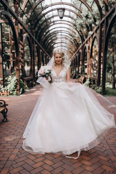 Parkta çiçek demeti tutan gelinlik içinde güzel bir gelin.         