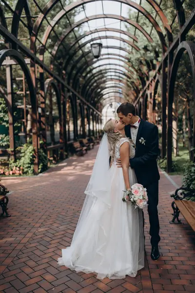 Genç gelin ve damat güzel bahçede öpüşüyor.    