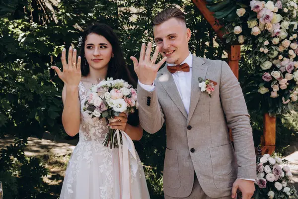 Güzel genç bir çift düğün günlerinde yüzüklerini dekorasyonun önünde gösteriyor.  