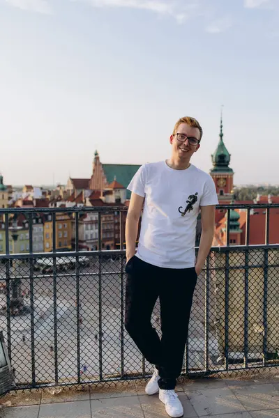 Genç yakışıklı adam eski şehirde çatıda poz veriyor. 