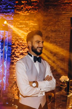 Mutlu genç adam kollarını kavuşturup partide gülümsüyor.