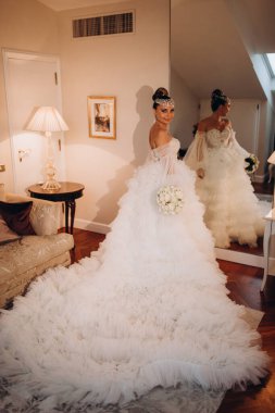 Lüks içinde poz veren beyaz gelinlik içindeki güzel gelinin portresi.