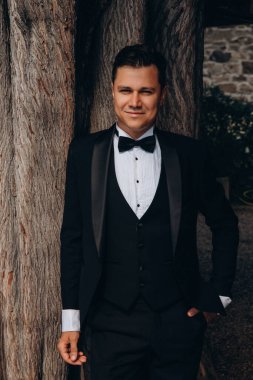 Siyah takım elbiseli, papyonlu genç gülen damadın portresi.