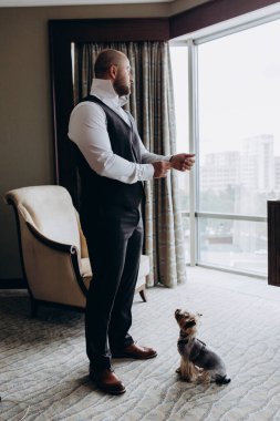 Şık ve mutlu genç damat ve lüks içinde şirin küçük bir köpeği var..        