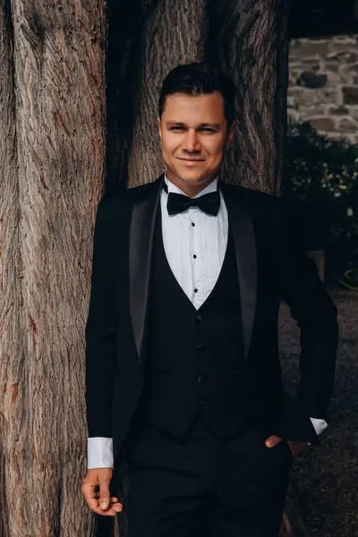 Siyah takım elbiseli, papyonlu genç gülen damadın portresi.