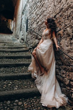 Gelinlikli güzel gelinin portresi. Eski kasabadaki merdivenlerde poz veriyor.                       