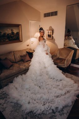 Lüks içinde poz veren beyaz gelinlik içindeki güzel gelinin portresi.