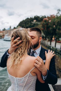 Gelin ve damat göl kıyısında öpüşüp sarılıyorlar. 