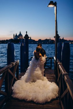 Güzel mutlu gelin ve damat Venedik 'te rıhtımda sarılıyor.      