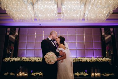 Güzel gelin ve damat düğün resepsiyonunda öpüşüyor