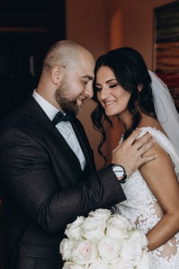 Güzel bir düğün çifti içeride sarılıp gülümsüyor.