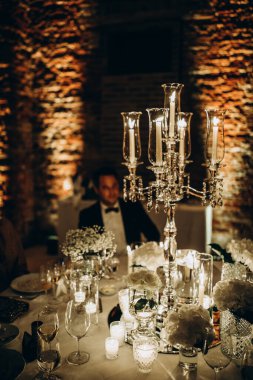 Düğün masasında mumlar ve damat arkada oturuyor.