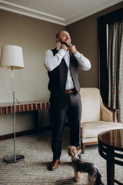 Şık ve mutlu genç damat ve lüks içinde şirin küçük bir köpeği var..        