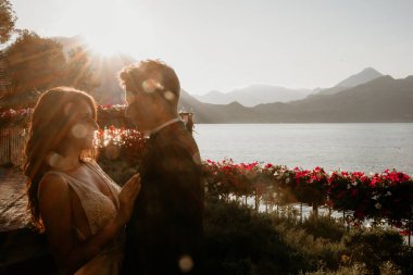 Gün batımında göl kenarında kucaklaşan genç gelin ve damat.       