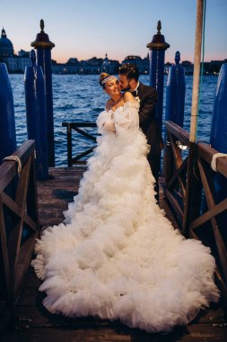 Güzel mutlu gelin ve damat Venedik 'te rıhtımda sarılıyor.      