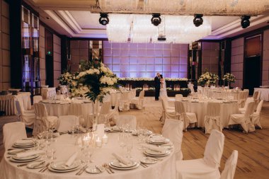 Gelin ve damat düğün salonunda servis masalarıyla 