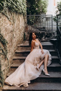 Gelinlikli güzel gelinin portresi. Eski kasabadaki merdivenlerde poz veriyor.                       