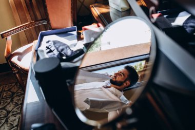 Beyaz gömlek giyen yakışıklı genç adamın aynadaki yansıması.