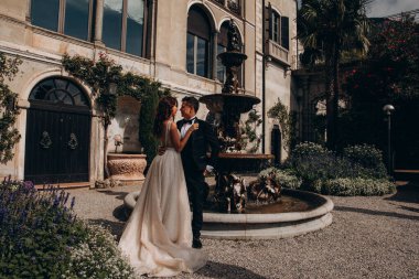 Mutlu gelin ve damat eski kasabada kucaklaşıp poz veriyor.