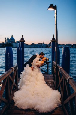 Güzel mutlu gelin ve damat Venedik 'te rıhtımda sarılıyor.      