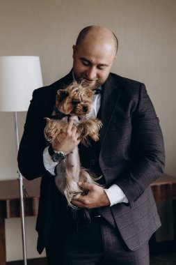 Şık ve mutlu genç damat ve lüks içinde şirin küçük bir köpeği var..        