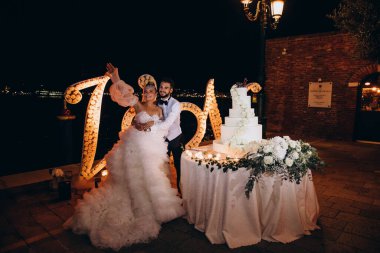 Mutlu gelin ve damat güzel düğün pastasının yanında sarılıyor. 