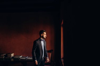 Resmi takım elbiseli genç yakışıklı adam odada poz veriyor.