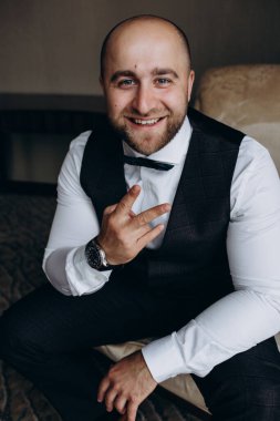 Resmi takım elbiseli genç yakışıklı adam odada poz veriyor.