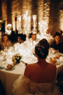 Düğün masasında oturan zarif elbiseli güzel gelinin arka manzarası.