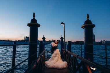 Güzel mutlu gelin ve damat Venedik 'te rıhtımda sarılıyor.      