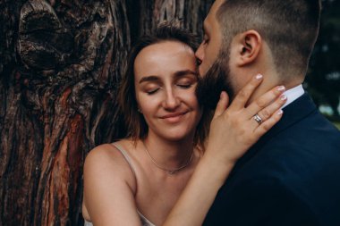 Gelin ve damadın parkta sarılıp öpüşmelerinin yakın plan görüntüsü.