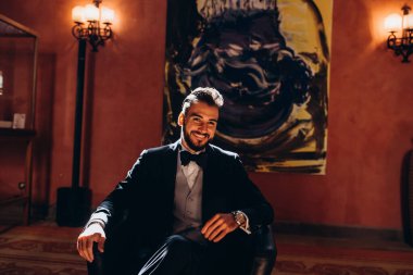 Resmi takım elbiseli genç yakışıklı adam odada poz veriyor.