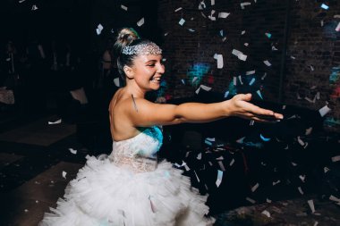 Gece konfetiyle dans eden beyaz elbiseli mutlu bir gelin. 