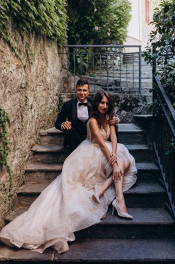 Eski kasabadaki merdivenlerde poz veren mutlu genç bir çiftin portresi.                           