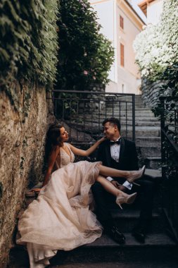 Eski kasabadaki merdivenlerde poz veren mutlu genç bir çiftin portresi.                           