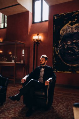 Resmi takım elbiseli genç yakışıklı adam odada poz veriyor.