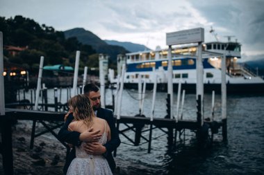 Birbirlerine aşık çiftler göl kıyısında kucaklaşıyorlar.