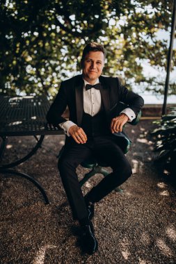 Genç gülen damadın portresi ahşap bankta oturuyor.