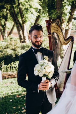 Ellerinde düğün buketiyle dışarıda duran mutlu genç damat.