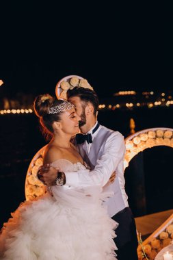 Güzel gelin ve damat geceleri dışarıda sarılıp öpüşüyor.