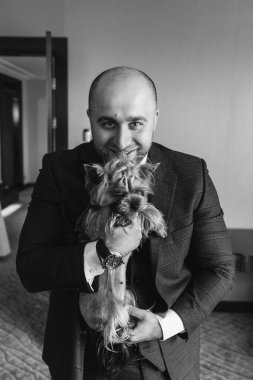 Şık ve mutlu genç damat ve lüks içinde şirin küçük bir köpeği var..        