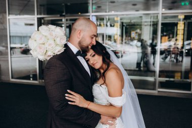 Güzel bir düğün çifti şehirde sarılıp poz veriyor.