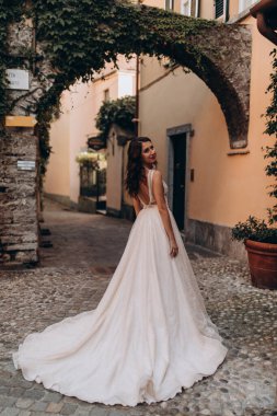 Beyaz gelinlikli güzel gelin eski kasaba caddesinde poz veriyor.                