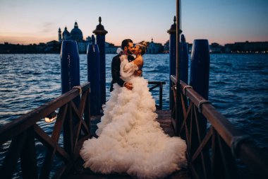 Güzel mutlu gelin ve damat Venedik 'te rıhtımda sarılıyor.      