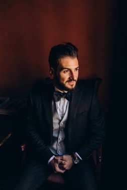 Resmi takım elbiseli genç yakışıklı adam odada poz veriyor.