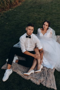 Mutlu gelin ve damat çimlerin üzerinde oturuyor..