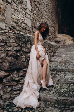 Gelinlikli güzel gelinin portresi. Eski kasabadaki merdivenlerde poz veriyor.                       