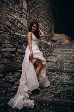 Gelinlikli güzel gelinin portresi. Eski kasabadaki merdivenlerde poz veriyor.                       