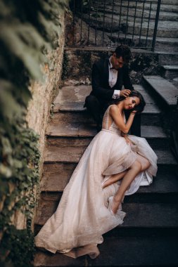 Eski kasabadaki merdivenlerde poz veren mutlu genç bir çiftin portresi.                           