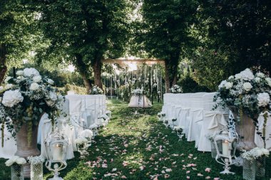 Çiçekli düğün kemeri ve yeşil çimlerin üzerinde sandalyeler